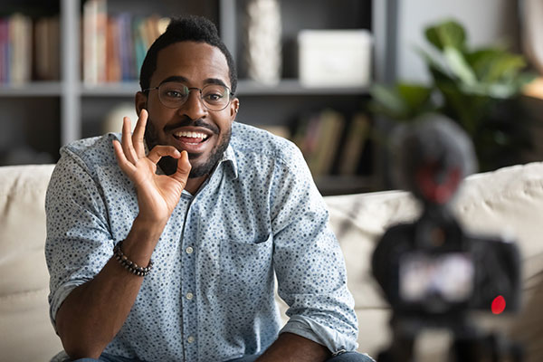 a black man sits in front of a camera giving a presentation